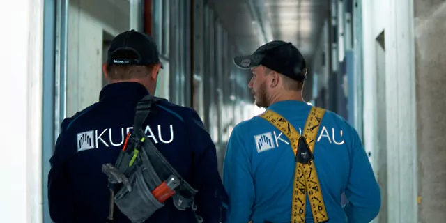 “Bauunternehmenmitarbeiter” Zwei Mitarbeiter des Bauunternehmens Kubau GmbH unterhalten sich während eines des laufens auf einem Baustellenflur